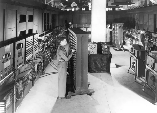 The ENIAC computer in 1946: two operators at a wall of vacuum-tube panels and patch cables.