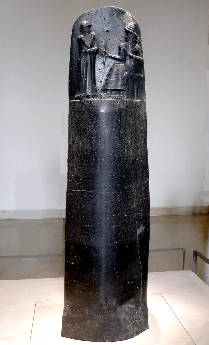 The upper part of the basalt stele of the Code of Hammurabi, showing the king standing before the seated sun god Shamash above a field of cuneiform.